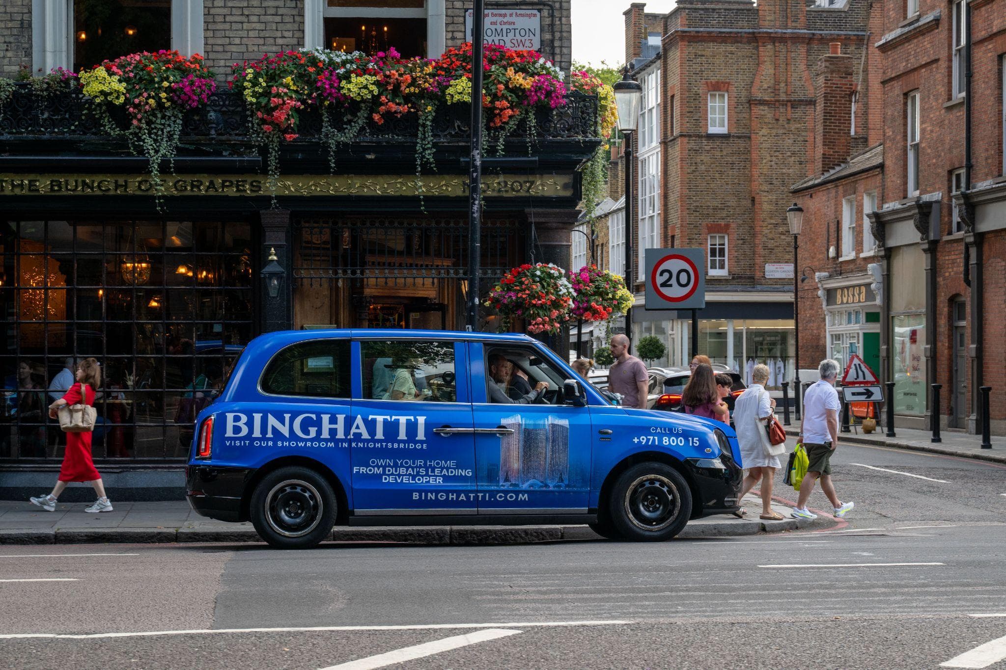 A blue Binghatti full wrap on a London black cab, on a Knightsbridge street