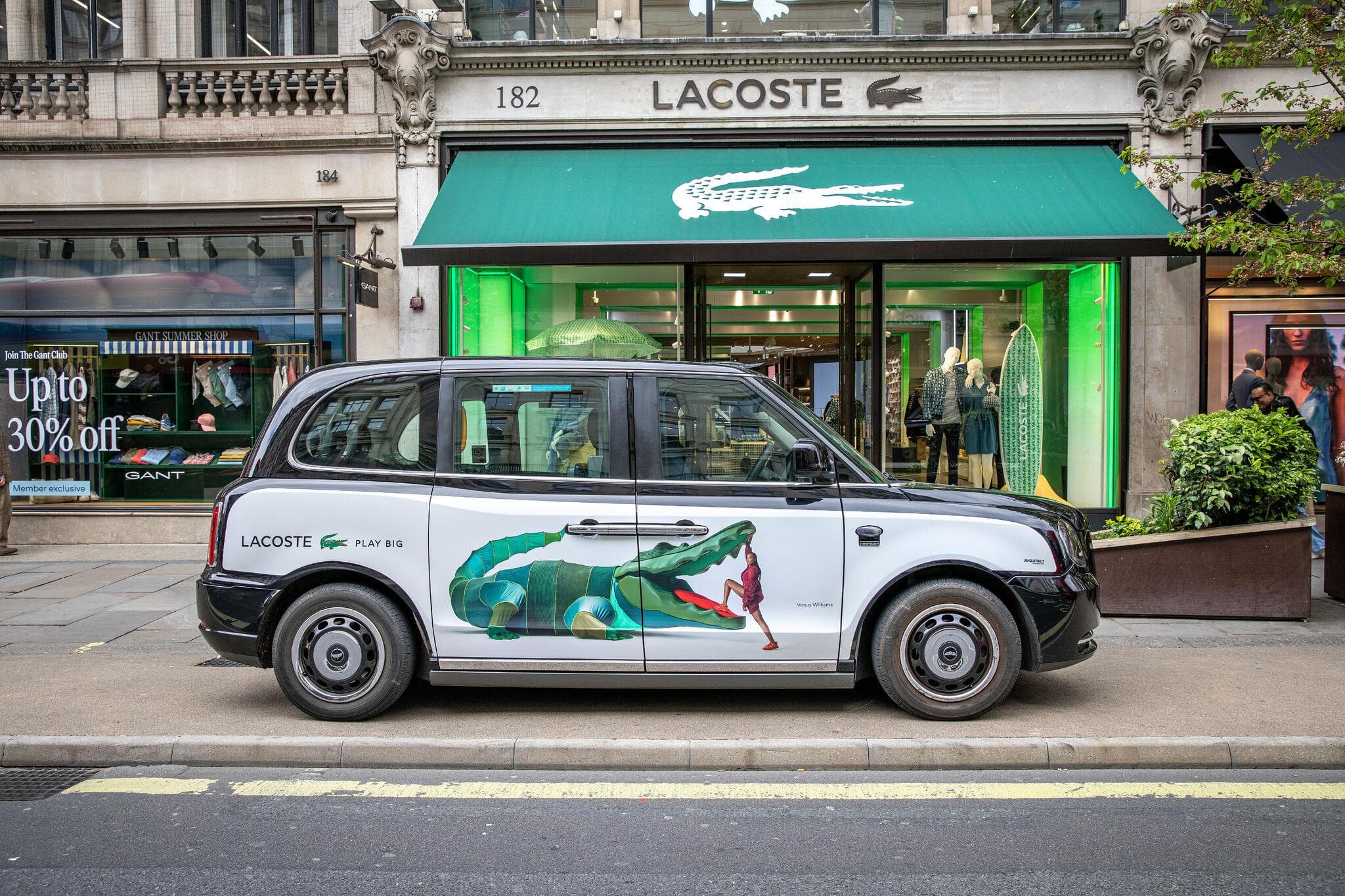 A Lacoste superside panel on an electric black cab outside the Lacoste store on Regent Street