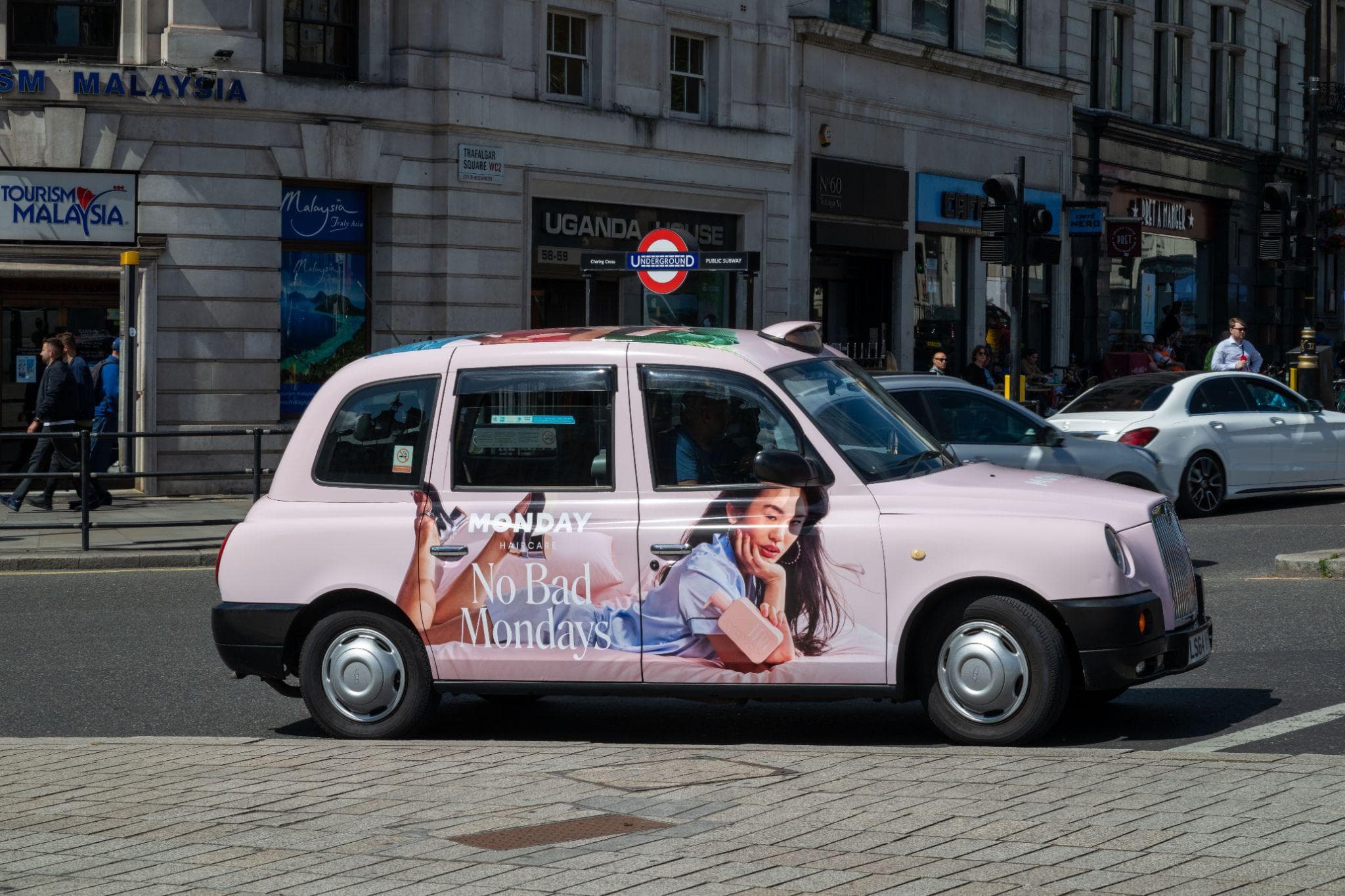 A pink Monday Haircare full wrap on a classic black cab on a central London street