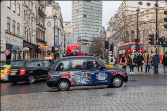 Superside advertising panel fitted along the side of a classic London black cab in city-centre traffic