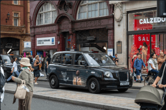 Superside advertising panel fitted to the flank of a premium electric black cab on a busy London shopping street