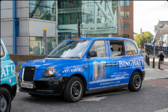 Premium electric black cab wrapped in a full vinyl livery, photographed on a London street